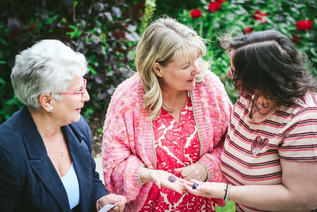 Three women enjoying a lively conversation in a garden setting.